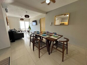 A dining area with a wooden table, chairs, and a television on the wall. - Depto. 2 rec. frente al Mar (Bahia) (Boca del Río)