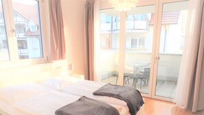A bedroom with a bed, two pillows, a window, and a sliding glass door leading to an outdoor area. - Ferienwohnung Badnerstraße L4 (Endingen am Kaiserstuhl)