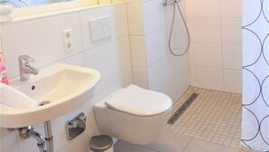 A bathroom with a sink, toilet, shower, and a mirror. - Ferienwohnung Badnerstraße L4 (Endingen am Kaiserstuhl)