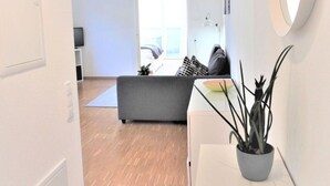 A modern living room with a sofa, a potted plant, and a large mirror. - Ferienwohnung Badnerstraße L4 (Endingen am Kaiserstuhl)