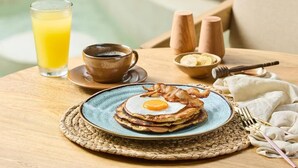 A breakfast setting with pancakes, a cup of coffee, and a glass of orange juice on a wooden table. - Holistic EcoHotel (San Nicolás)
