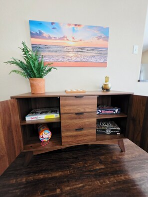 A wooden cabinet with two drawers, a potted plant, and a painting of a sunset. - Charming 2-bedroom House Near Rockport's Downtown Cultural District (Rockport)