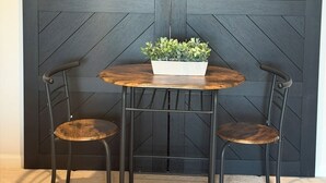 Une pièce dotée d’une grande porte coulissante, de deux chaises, d’une petite table avec une plante et d’un sol recouvert d’une moquette.