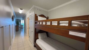 Ein Hotelzimmer mit Etagenbetten, einem Schild, das das Verbot von Gepäckwagen im Zimmer anzeigt, und Blick auf den Flur.