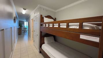Une chambre d’hôtel avec des lits superposés, un panneau indiquant qu’il n’y a pas de chariots à bagages disponibles dans la chambre, et une vue sur le couloir.