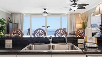 A modern kitchen with a large window, a ceiling fan, and a view of the ocean.