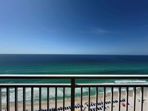A beach view from a balcony with a railing, ocean, and beachgoers. - Oceanfront, 23rd floor Condo, Pools, Gym, Wifi (Panama City Beach)