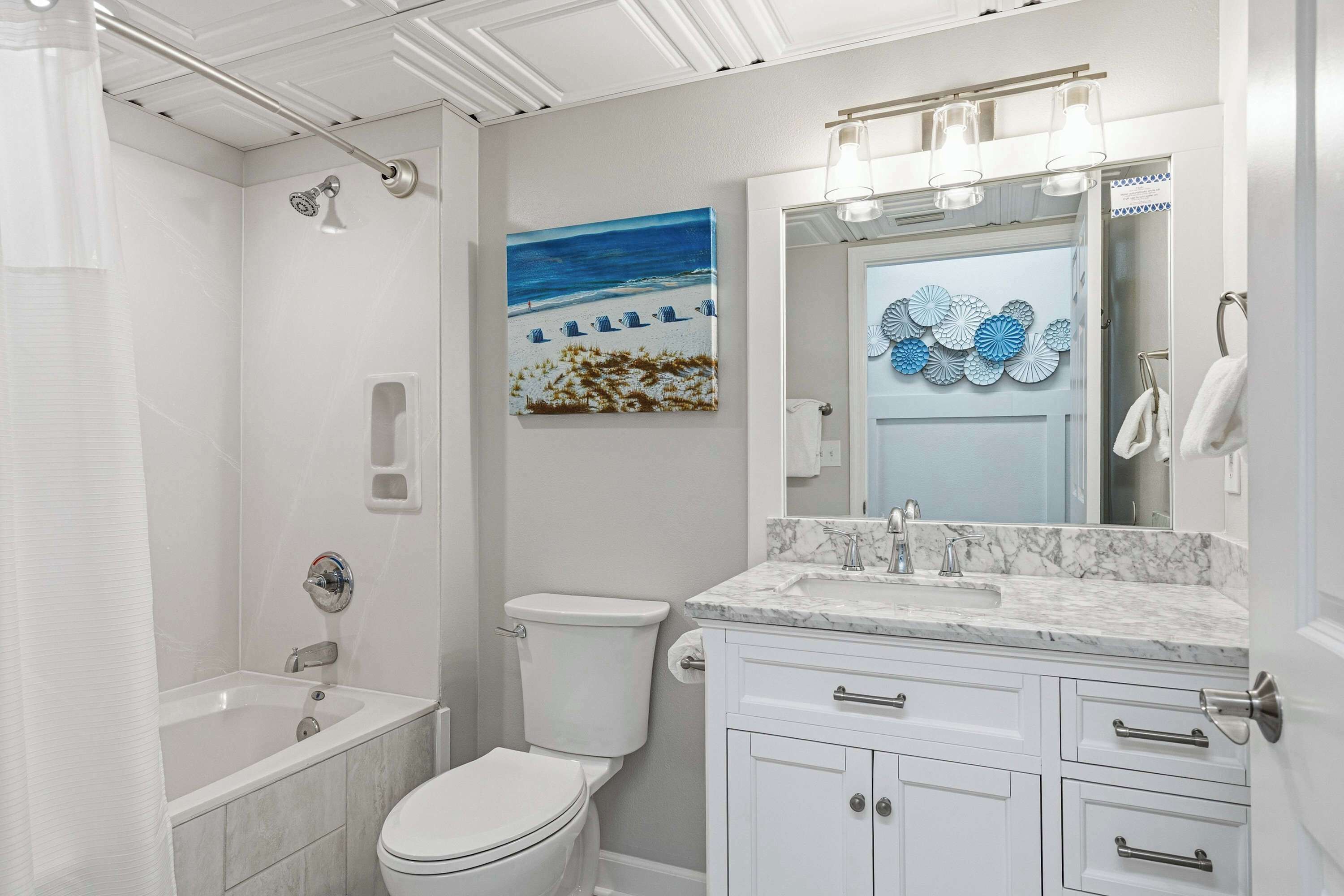Un baño moderno con bañera, inodoro y tocador con lavabo y espejo.