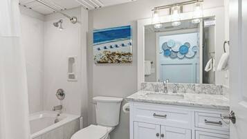 Un baño moderno con bañera, inodoro y tocador con lavabo y espejo.