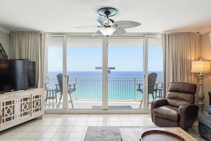 A hotel room with a balcony, a television, a leather chair, and a lamp. - Oceanfront, 23rd floor Condo, Pools, Gym, Wifi (Panama City Beach)