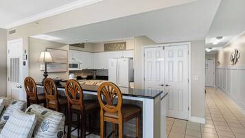 A kitchen with white cabinets, a central island, and a dining area with wooden chairs and a table.