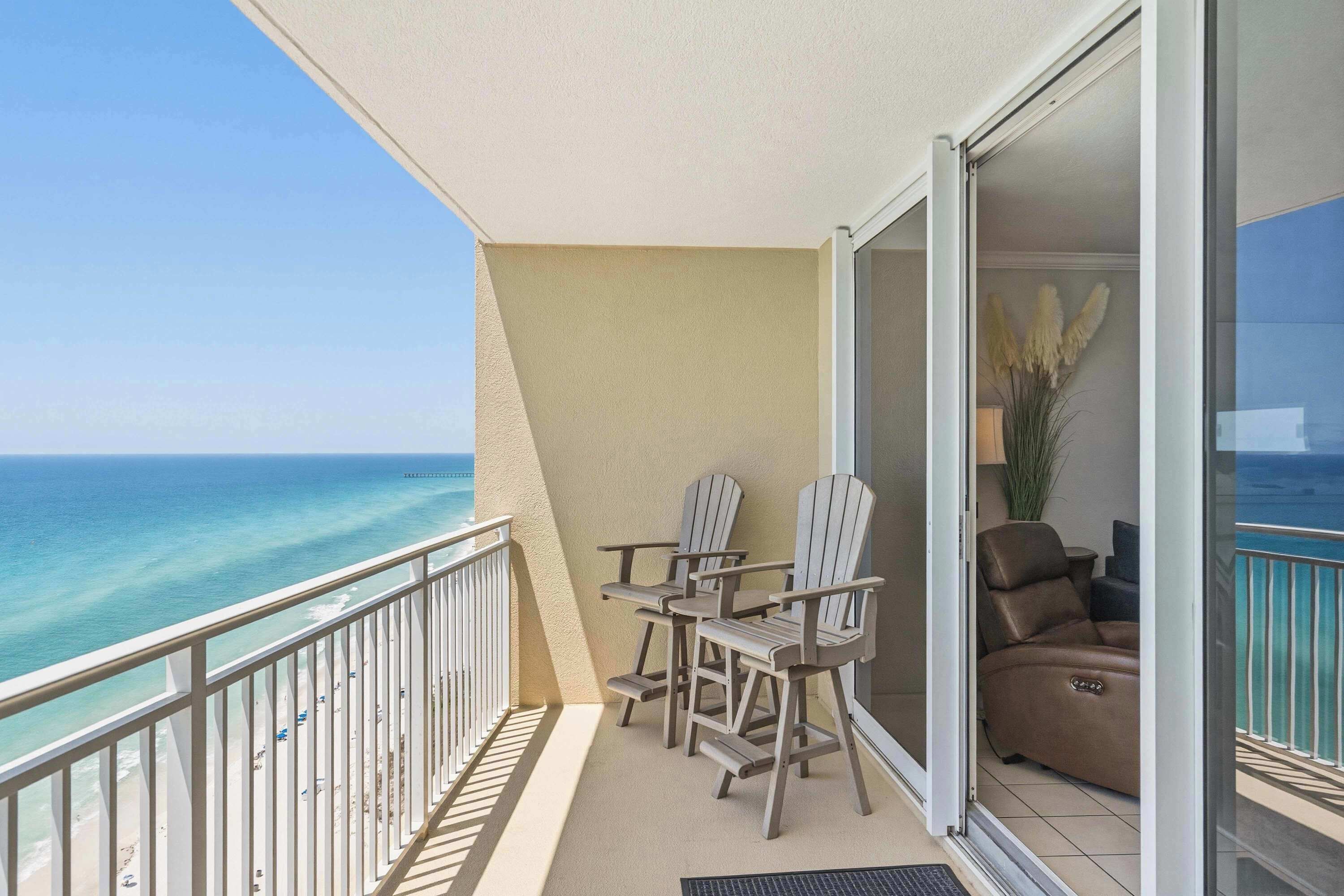 Un balcone con vista sull'oceano, due poltrone Adirondack, un divano e una pianta in vaso.