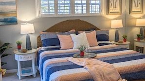 Una camera da letto con un letto, comodini, una ventola a soffitto, una finestra con persiane e decorazioni alle pareti.