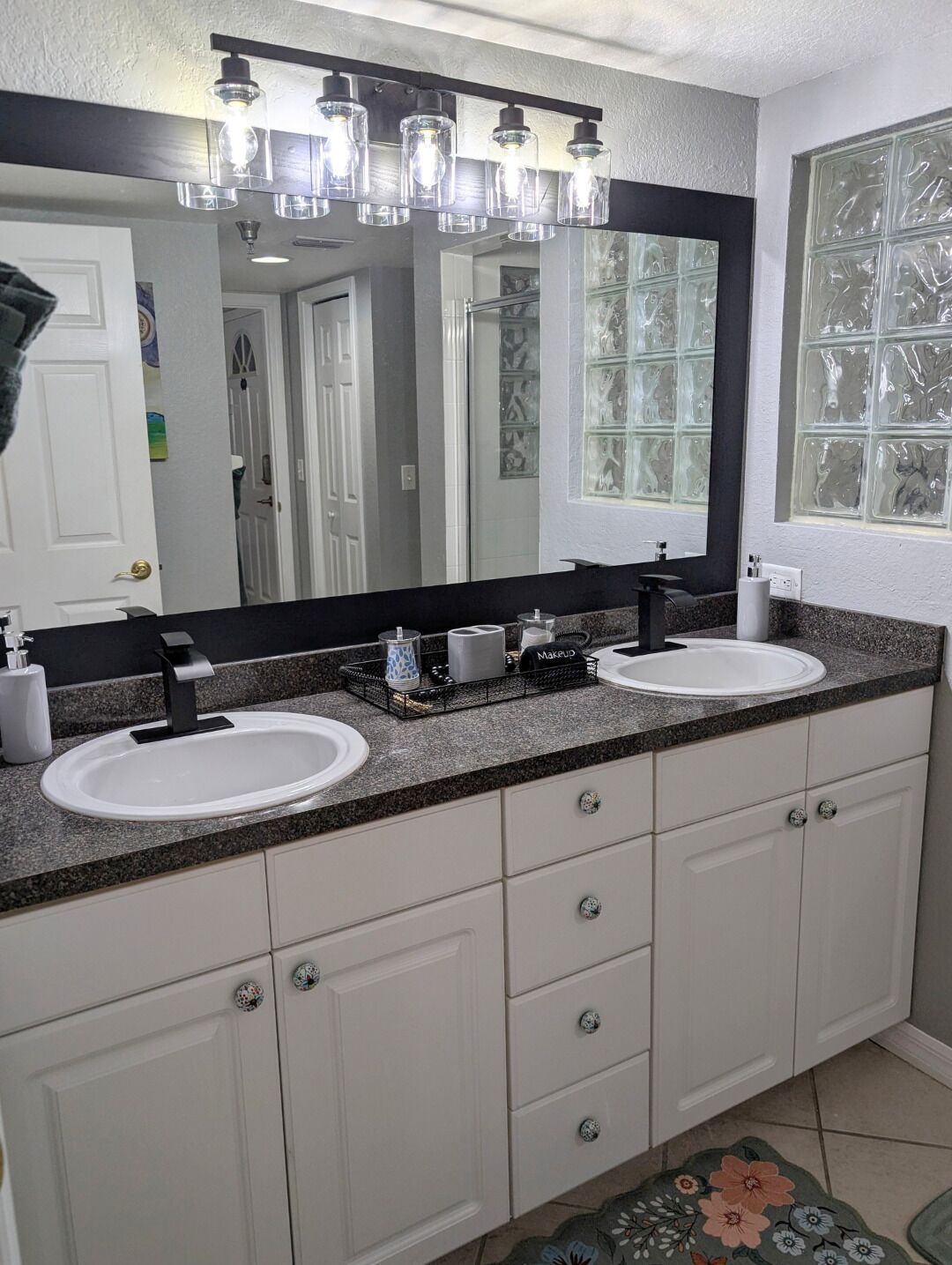A bathroom with two sinks, a large mirror, and a window with frosted glass.
