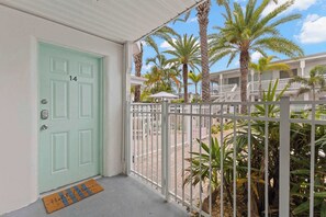 A light green door with a keypad lock, a white metal gate, and a doormat with a signature. - Handicap Accessible Suite in Clearwater Beach (Clearwater)