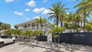 A hotel with a white facade, a black fence, and palm trees in the foreground. - Handicap Accessible Suite in Clearwater Beach (Clearwater)