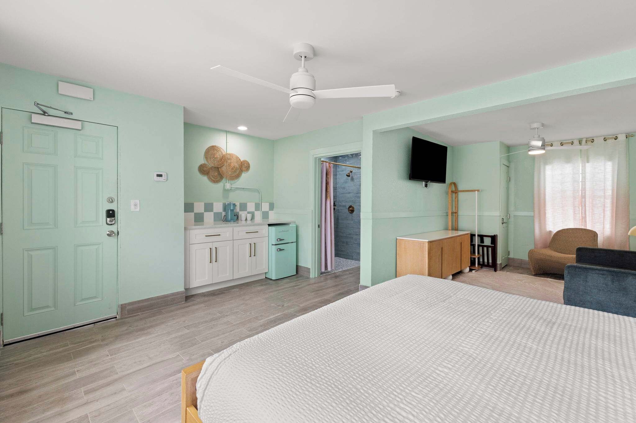 Une chambre à coucher comprenant un lit, un bureau, une chaise, une télévision et une douche.