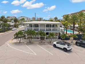 A two-story building with a balcony, surrounded by palm trees and a parking lot. - The Bunk Room | Sparkling Pool, Steps to the Beach (Clearwater)