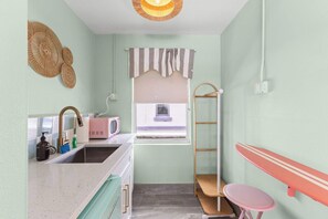 Cocina compacta con un lavamanos, microondas y una pequeña ventana.