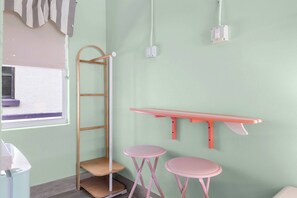 A room with a wooden ladder, two pink stools, a wall-mounted shelf, and a window with a curtain. - The Cabana Suite | Steps to the Beach! (Clearwater)