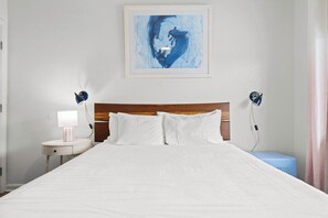 A neatly made bed with white bedding, a wooden headboard, and two bedside lamps. - NEW! North Petite Room | Steps to the Beach! (Clearwater)