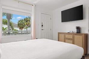 Ein Hotelzimmer mit einem Bett, einem an der Wand montierten Fernseher, einem Holzschrank und einer Tür.