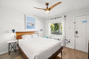 Ein Hotelzimmer mit Bett, Deckenventilator, Fenster mit Blick, Tür und einem kleinen Tisch.