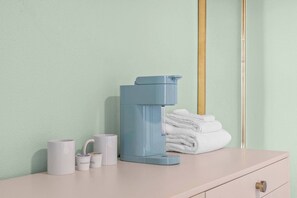 Un baño con inodoro, una pila de toallas y algunos artículos de aseo en un mostrador.