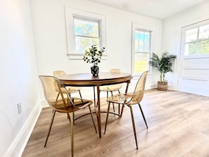 Et spiseområde med et rundt træbord, fire stole og en potteplante.