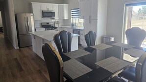 A modern kitchen with white cabinets, stainless steel appliances, and a dining area with a glass table and chairs.