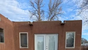 Un patio exterior con mesa y sillas, una parrilla y una puerta corrediza de vidrio.