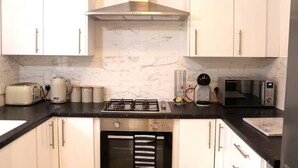 A kitchen with white cabinets, a gas stove, a microwave, and a toaster. - Central 3 Bed Home, Parking Garden Milton Keynes (Bradwell Common)