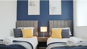 A double bed room with two nightstands, a lamp, and wall art. - Central 3 Bed Home, Parking Garden Milton Keynes (Bradwell Common)