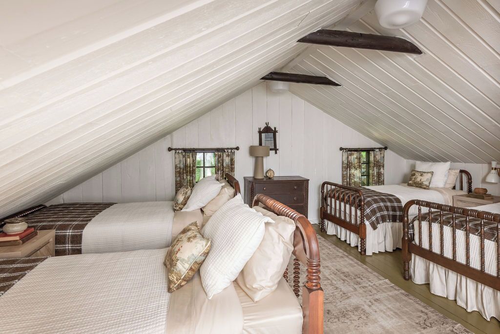 A bedroom with two beds, a wooden ceiling, and a large window.