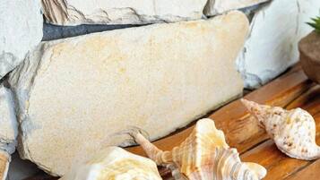 A stone wall with a wooden bench and seashells.