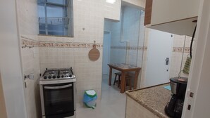 A compact kitchen with a gas stove, a coffee maker, and a small dining table. - Quiet apartment, excellent location in Copacabana, 5 minutes from the beach. (Rio de Janeiro)