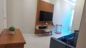 A modern living room with a wooden TV stand, a small table with a plant, a sofa, and a grey partition. - Quiet apartment, excellent location in Copacabana, 5 minutes from the beach. (Rio de Janeiro)