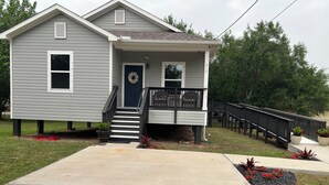 A two-story house with a front porch, a staircase, and a front yard with a walkway. - Home away from home (Palacios)