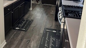 A kitchen with dark cabinets, a stainless steel sink, a black refrigerator, and a gas stove. - Home away from home (Palacios)
