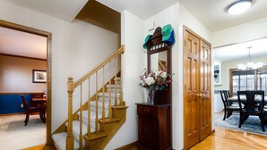 A wooden staircase, a wooden door, a dining area with a table and chairs, and a hallway with a rug. - The Ultimate Irish Getaway | 1.5 Miles from Campus (South Bend)