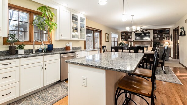 A modern kitchen with granite countertops, white cabinetry, and a central island with bar stools. - The Ultimate Irish Getaway | 1.5 Miles from Campus (South Bend)