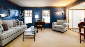 A living room with a sofa, armchair, coffee table, lamp, and piano. - The Ultimate Irish Getaway | 1.5 Miles from Campus (South Bend)