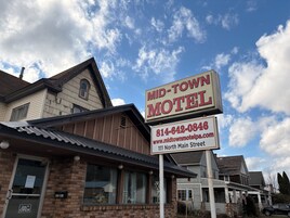 Señal de motel con el nombre 'MID-TOWN MOTEL' e información de contacto.