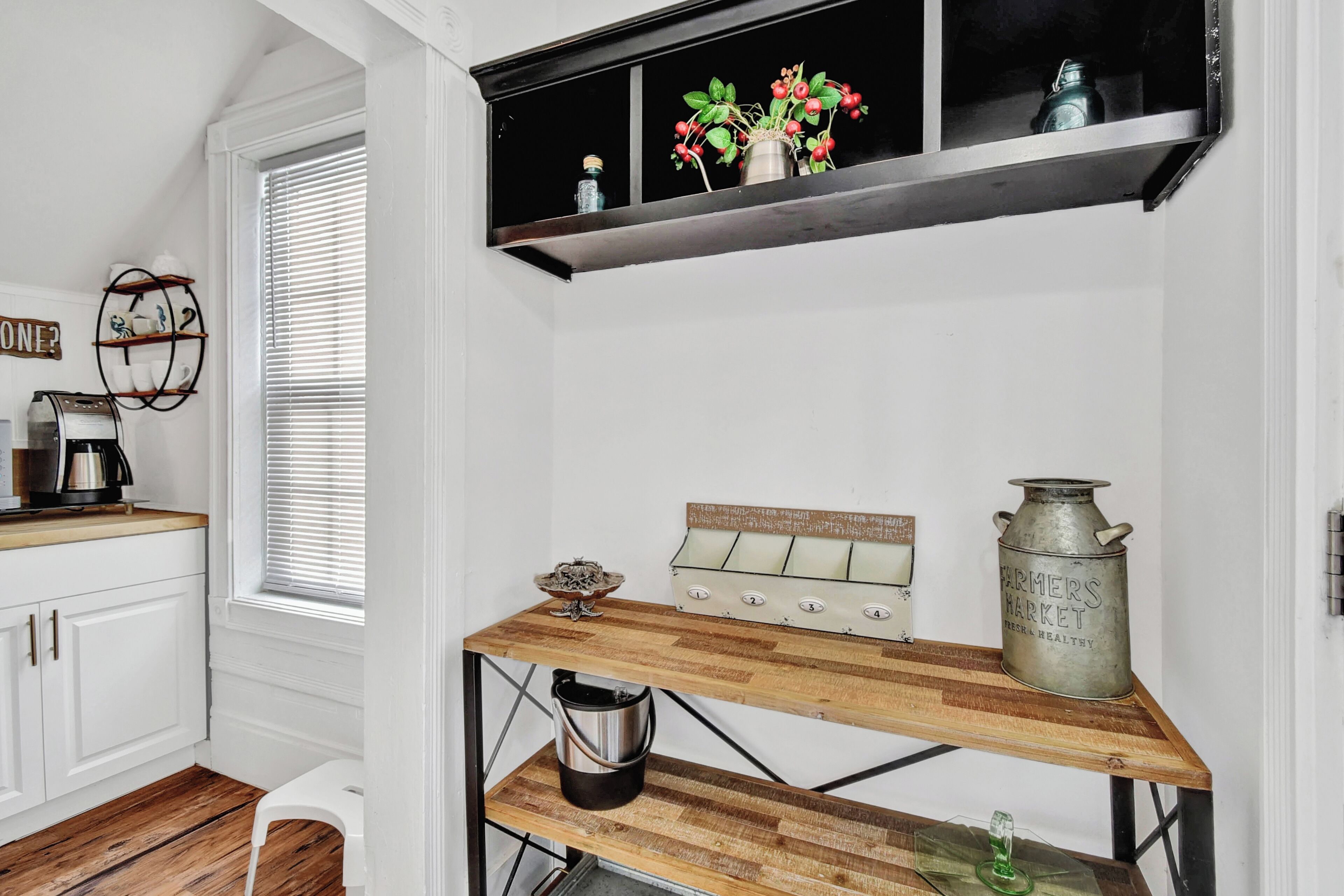 A kitchen with white cabinets, a wooden countertop, a black shelf with decorative items, and a vintage-style stove.