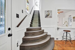 Eine Treppe mit einem gemusterten Teppich, einem Holnändergeländer und einer Wandleuchte.