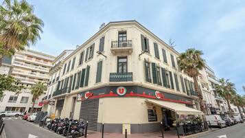A corner building with a cafe named "Utile" on the ground floor, featuring a balcony and a row of parked motorcycles.