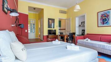 A hotel room with a bed, a desk, a chair, a sofa, and a television.