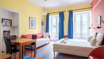 A room with a bed, a desk, a chair, and a window with curtains.