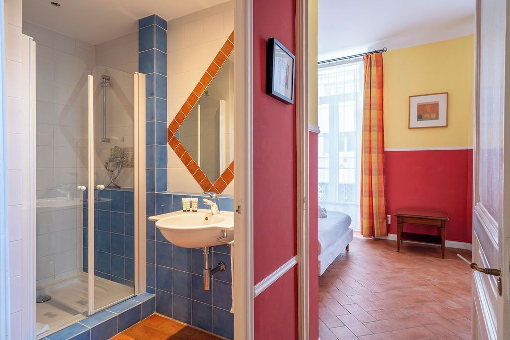 A bathroom with a glass shower enclosure, a white sink, and a mirror with a geometric tile backsplash.
