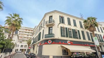 A Uitaly hotel with a white facade, green shutters, and a balcony.